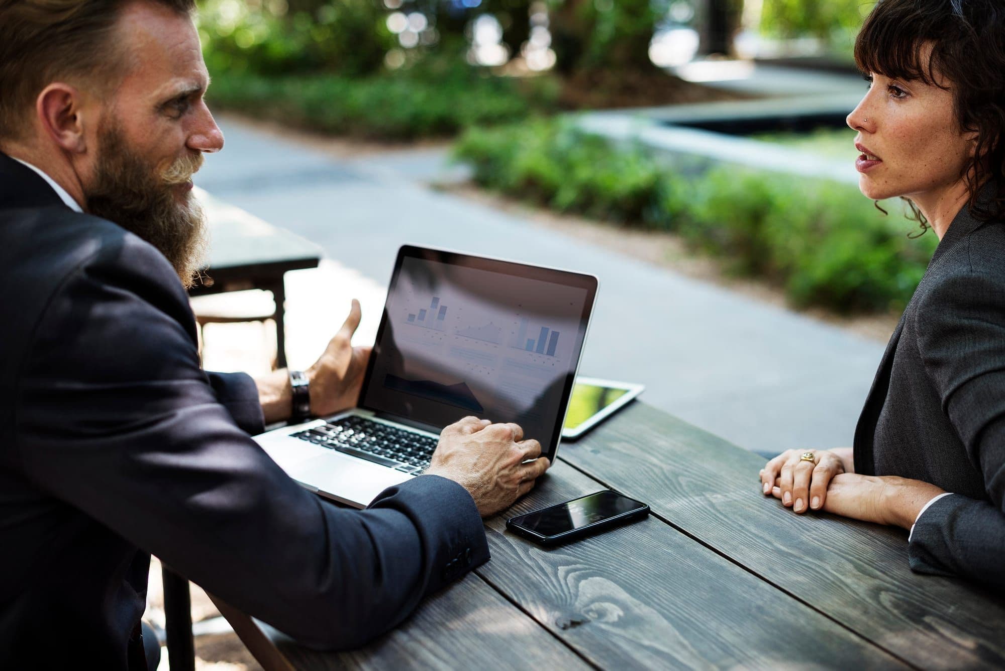Two colleagues discussing results on a laptop at an outdoor table