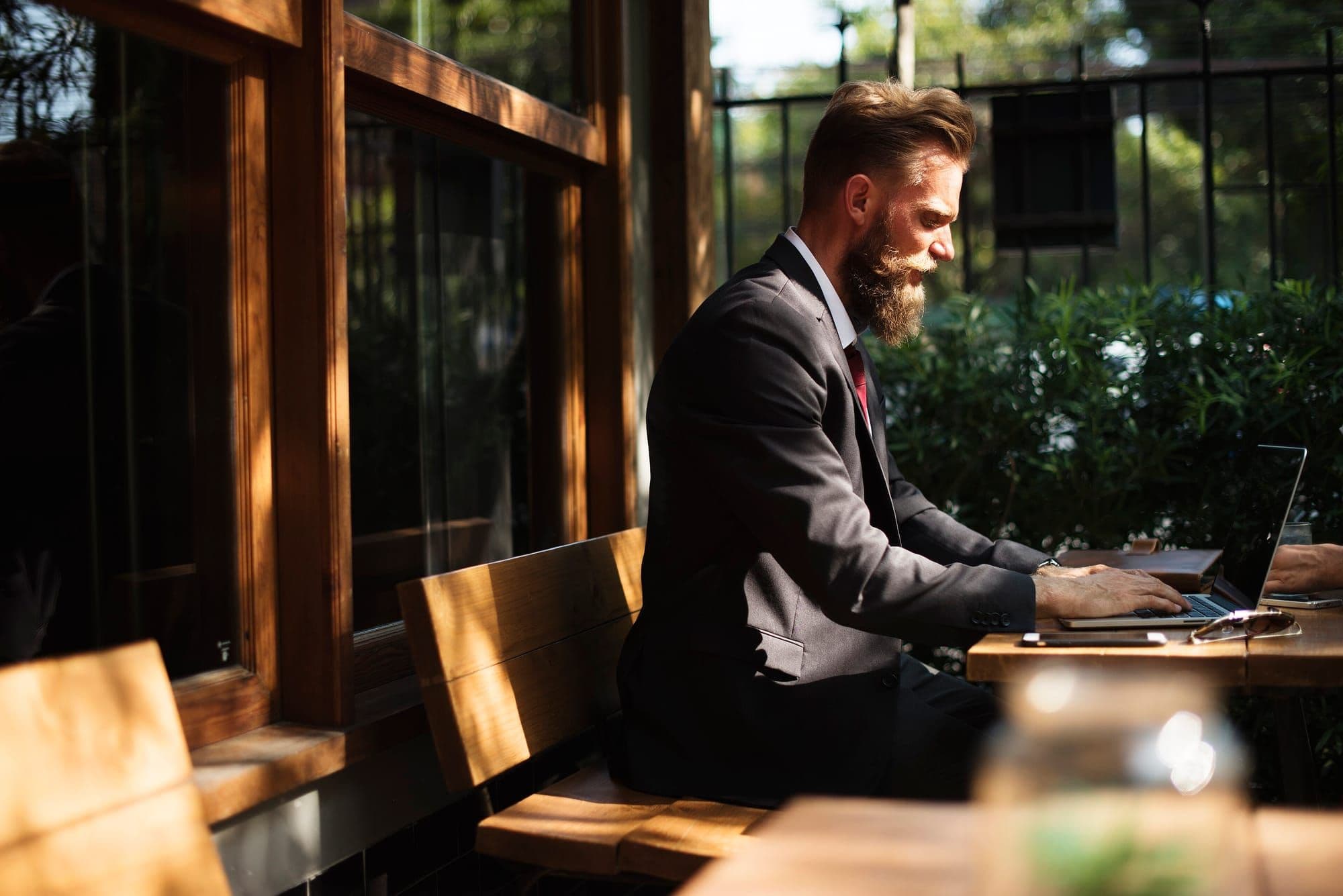 Professional in a suit working on a laptop outdoors